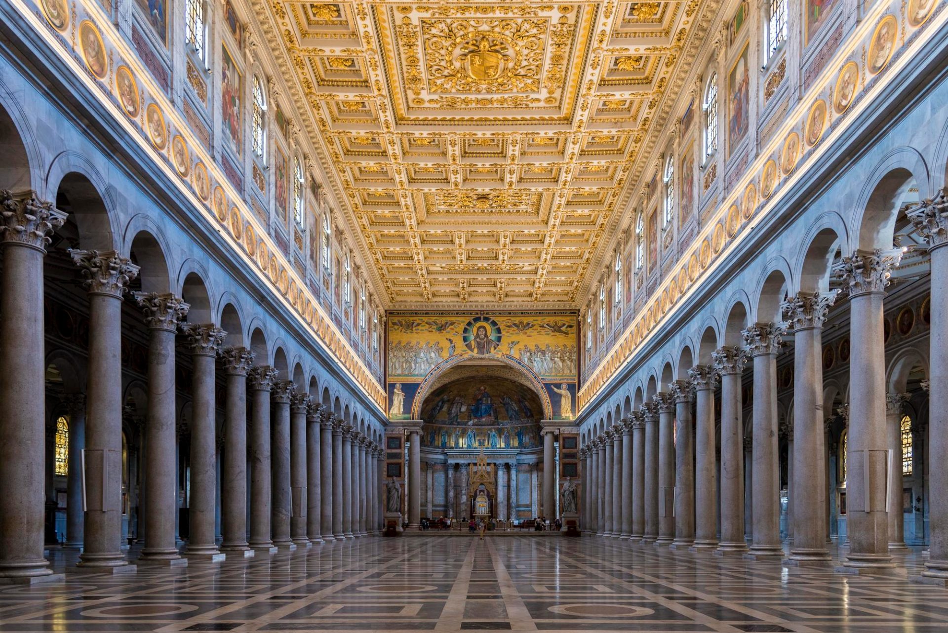 Grand basilica interior with long colonnades, ornate ceiling, and a central apse.